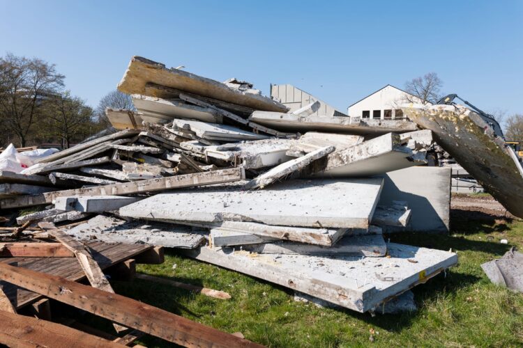 Großer Haufen aus Beton- und Bauschuttplatten auf einer Grünfläche