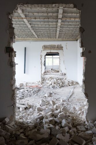 Blick durch eine durchbrochene Wand auf eine entkernte Baustelle mit Bauschutt