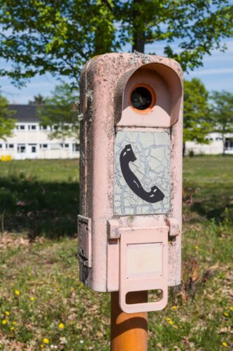 Historischer Überwachungspfosten mit Telefon-Symbol auf einer Wiese