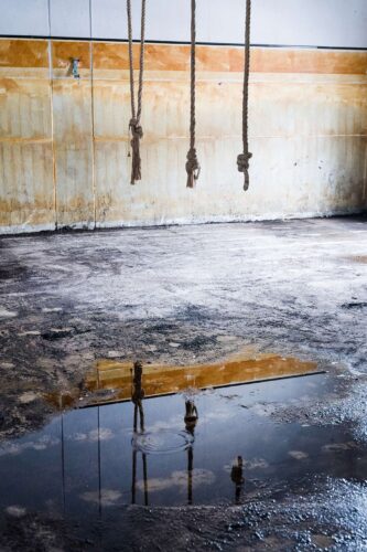 Leerer Industrieinnenraum mit nasser Bodenfläche und Wasserpfütze