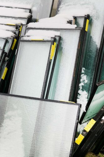 Gestapelte Fensterrahmen mit Schnee auf der Baustelle