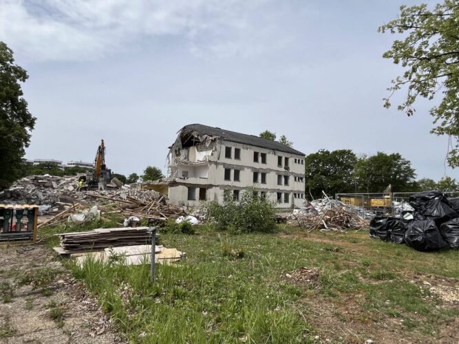 Abriss eines mehrstöckigen Gebäudes mit Bauschutt und Bagger