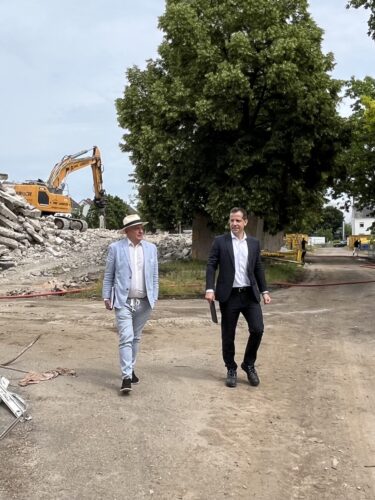 GVG-Geschäftsführer Franz Ringhoffer und Oberbürgermeister Nino Haase auf einer Baustelle mit Bagger und aufgeschüttetem Material